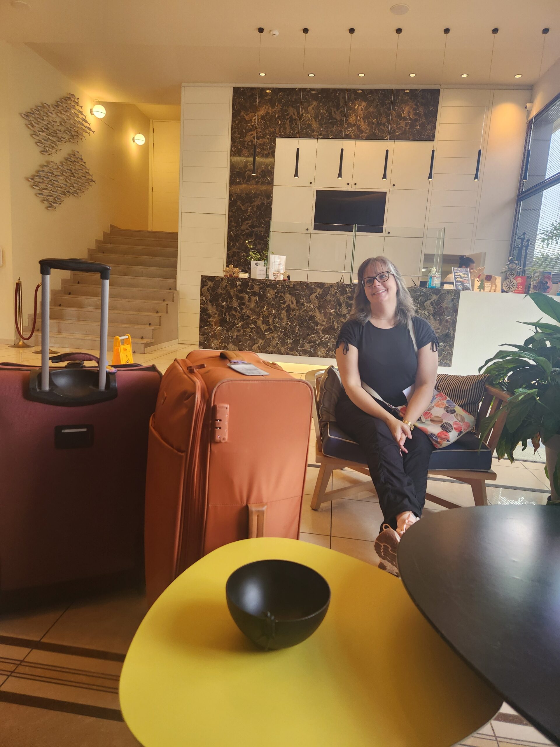 Traci sitting next to luggage in hotel lobby